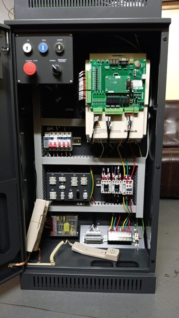 Open elevator control panel with controller, electrical wiring, circuit breakers, relay modules, emergency controls, and communication handset installed for elevator operation by Islamabad Elevator Solutions.